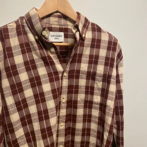 Rutig skjorta från Our Legacy - Snygg rutig skjorta i vinrött och beige från Our Legacy. Skjortan är i grymt skick och perfekt nu till våren! 