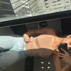 Beige ärmlös linnetopp - Säljer en stilren beige linnetopp med smala axelband. Perfekt för varma dagar och enkel att matcha med olika outfits. Toppen har en tight passform som framhäver figuren.