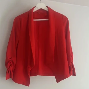 Röd kavaj  - Snygg röd kavaj med unika ärmar. Perfekt för att ge en färgklick till din outfit. Den har en öppen design utan knappar