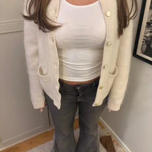 Vit kofta med knappar - Säljer en mysig vit kofta med knappar framtill. Koftan har långa ärmar och två fickor. Extremt fin i kashmir.