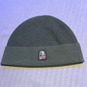 Mörkgrön mössa från Parajumpers - Snygg mössa från Parajumpers med ribbad kant och broderad logotyp framtill. Perfekt för att hålla värmen under kyliga dagar.
