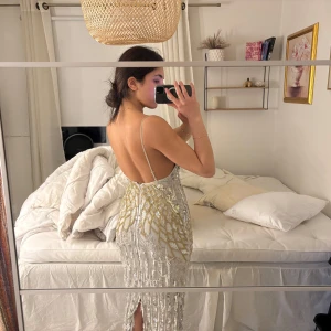 Glittrig klänning med paljetter - Säljer en fantastisk glittrig klänning med fransar och paljetter i silver och guld. Klänningen har en v-ringad design och smala axelband med mycket detaljer. Perfekt för en festligheter🙂‍↕️ klänningen är använd en gång, köpt från asos för 2000kr. Varan säljs inte längre på nätet!♥️OBS: ganska stor i storleken, funkar för en med storlek s/m också!!