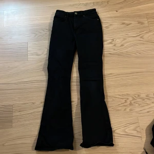 Svarta Peachy Flare jeans - Snygga svarta flare jeans från Peachy med hög midja och klassisk femficksdesign. De har en knapp och dragkedja framtill. Perfekta för en trendig look med utsvängda ben.