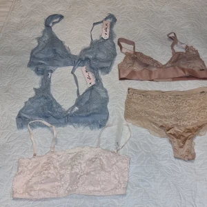 Spetsiga bhar i olika färger plus en trosa - Säljer tre  spetsiga bhar i blått, rosa och beige. Den blå och rosa  har smala axelband och spetsdetaljer, medan den beige toppen är mer täckande med bredare spetsmönster. Perfekta för att lägga till en romantisk touch till din outfit.Allt är helt nytt, utan lapp.