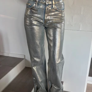 Silvriga jeansbyxor från Zara - Snygga silvriga jeansbyxor från Zara med en glittrig finish. Byxorna har en hög midja och en straight passform som ger en cool look. Perfekta för att sticka ut i mängden!