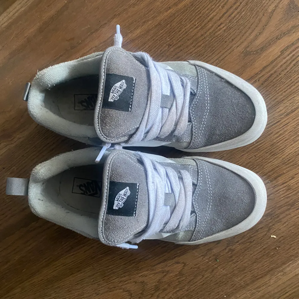 Snygga grå sneakers från Vans med vit sula och klassisk sidostrip. Skorna har snörning och är tillverkade i mocka och syntetmaterial. Perfekta för en avslappnad stil.. Kengät.