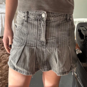 Grå jeanskjol med knappar zara - Snygg grå jeanskjol med subtila ränder och knappdetalj framtill. Minikjol med ljusa ”tänder”, volangkjol/veckad 