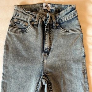 Ljusblå jeans med hög midja från Lager 157 - Snygga ljusblå jeans med hög midja och klassisk femficksdesign från Lager 157 i storlek XXS. Jeansen har en dragkedja och knapp framtill samt bälteshällor. Använda 1 gång. 