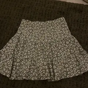 Söt blommig kjol från 157 New i grått och vitt. Kjolen har ett volangigt fall och ett charmigt blommönster. Perfekt för en somrig look!