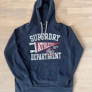 Superdry hoodie - Säljer denna extremt snygga Superdry hoodie med ett sjukt fett tryck. Hoodien är i nyskick, knappt använd och i storlek M. Hör av er vid eventuella frågor eller funderingar! 