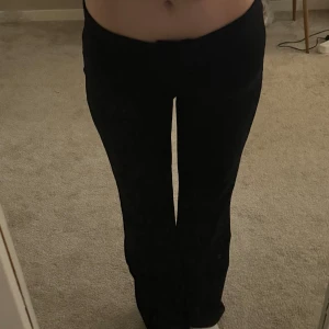 Svarta bootcut kostymbyxor - Säljer ett par svarta bootcut byxor med låg midja från lager 157. De har en stilren och enkel design utan synliga detaljer eller fickor. Materialet är stretchigt och bekvämt, perfekt för dig som gillar en klassisk look med lite utsvängda ben. Säljer för att jag köpte fel storlek 