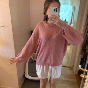 Rosa stickad tröja  - Mysig rosa stickad tröja med rund halsringning och långa, lite pösiga ärmar. Tröjan har en loose passform och ribbade muddar vid ärmslut och nederkant. Perfekt för lager-på-lager och chill dagar.