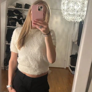 Vit stickad croppad topp - Supermysig vit stickad topp med korta ärmar. Tröjan är i nyskick och knappt använd