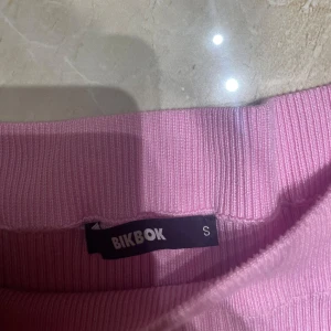 Ribbad offshouldertröja från BikBok - Säljer en ljusrosa ribbad offshouldertröja från BikBok i storlek S. Tröjan har lång ärm och är figurnära med stretchigt material. Perfekt för dig som gillar en feminin och trendig look. Superfin att styla med jeans eller kjol! 