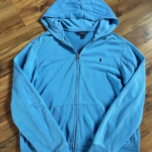Blå hoodie från Polo Ralph Lauren  - Ljusblå hoodie från Polo Ralph Lauren i storlek XL som barn, men S i vuxen. Tröjan är i 8/10 skick skulle ja säga med en liten fläck på framsidan men de går o tvätta 🧽Måtten på tröjan är 64 cm på längden o 46 cm på bredden. Pris går såklart att diskutera 🤝 hör av er!! 