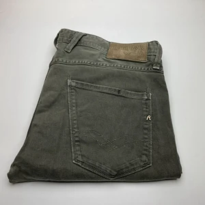 Replay Anbass grå jeans - Snygga grå jeans från Replay, modell Anbass. Klassisk femficksdesign med diskret logga på bakfickan och läderpatch i midjan. Jeansen har en modern passform och är tillverkade i mjukt bomullsmaterial med lite stretch för extra komfort.