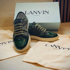 Gröna sneakers från Lanvin i mocka - Snygga gröna sneakers från Lanvin med ovandel i mocka och lackad tå. Skorna har rund tå, snörning och vit platt sula. Perfekta för dig som vill ha en stilren men ändå unik look. Kommer med original dustbags och box.