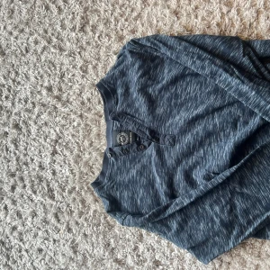 Blå långärmad tröja från Lindbergh - Storleken kan passa mindre storleken eftersom tröjan är köpt för så länge sen.Snygg blå långärmad tröja från Lindbergh med diskret mönster och knappar vid halsen. Tröjan har en avslappnad passform och är tillverkad i mjukt bomullsmaterial. Perfekt för dig som gillar stilrena och bekväma plagg.