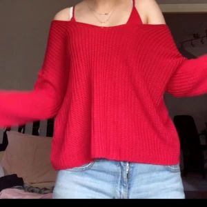 Röd offshoulder stickad tröja H&M - Säljer en röd stickad tröja från DIVIDED H&M i storlek XS. Tröjan har offshoulder-design med korsade band i ryggen, den är loose fit med långa ärmar. 