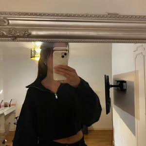 Svart stickad half zip från Gina Tricot - Mysig svart stickad tröja från Gina Tricot med half zip-dragkedja och croppad passform. Tröjan har långa ärmar och en lite loose vibe, perfekt till jeans eller kjol. Snygg krage som kan bäras öppen eller stängd.