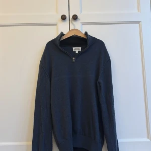 Mörkblå half zip tröja från Hartford - Mörkblå långärmad tröja från Hartford med half zip-dragkedja och hög krage. Tröjan är stickad och har en klassisk, avslappnad passform. Perfekt för dig som gillar stilrena och bekväma plagg med en tidlös vibe.