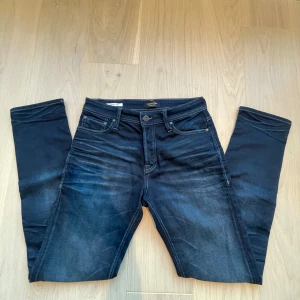 Mörkblå jeans från Jack & Jones - Snygga mörkblå jeans från Jack & Jones med klassisk femficksdesign. Jeansen är tillverkade i stretchigt denim för extra komfort. Perfekta för dig som gillar sköna men ändå stilrena jeans.