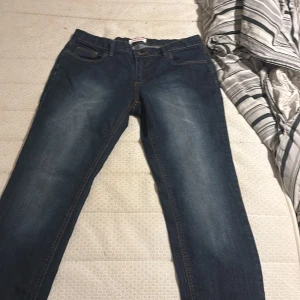 Mörkblå jeans från John Baner, strl 42 - Snygga mörkblå jeans från John Baner i storlek 42. Klassisk femficksmodell med kontrastsömmar och lätt slitning framtill och baktill. Jeansen har raka ben och är tillverkade i tåligt denimtyg. Perfekta till en avslappnad stil.