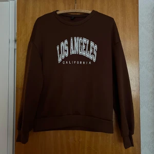 Brun sweatshirt - Mysig brun sweatshirt från SHEIN med trycket 'Los Angeles California' i vitt framtill. Teddyfleece foder inuti. Markerad som S men är oversized så skulle snarare säga M till passformen!❤️