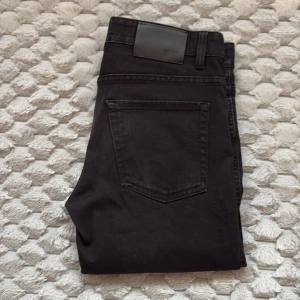 Svarta jeans från Hugo Boss - Snygga svarta jeans från Hugo Boss med klassisk femficksdesign och diskret logga på bakfickan. Jeansen har en rak passform. Perfekta till sneakers.