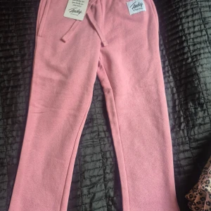 Ljusrosa mjukisbyxor från Frank Dandy - Säljer ett par ljusrosa mjukisbyxor från Frank Dandy. Byxorna har dragsko i midjan och är tillverkade i mjukt bomullsmaterial. Perfekta för chill dagar och har en relaxed passform. Snygg och enkel design med fickor på sidorna.