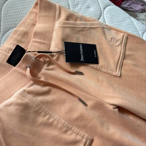 Juicy Couture Velour byxor - Säljer ett par jättefina velour byxor i peach/smutsrosa färg. Aldrig använda med prislapp kvar🩷Storlek M, passar L för den som vill ha dom lite tightare.