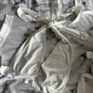 Vit topp med knyt från SHEIN - Supersnygg vit topp med knyt från SHEIN i storlek M. Modellen har breda band som knyts i nacken och ryggen för en justerbar passform. Materialet är mjukt och stretchigt.