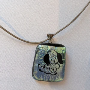 Glittrigt halsband med hundmotiv bland annat/ paket - Unikt halsband med ett glittrigt, fyrkantigt hänge i silverton och ett sött svartvitt hundmotiv. Hänget har en skimrande yta som fångar ljuset och sitter på en tunn, grå kedja. Perfekt för dig som gillar djur och vill sticka ut med din stil. Bland annat även militär lampa, en Mario figur, nyckelring djur och parfym. Parfymen är gammal men kan hällas ut. Då blir det bara flaskan.