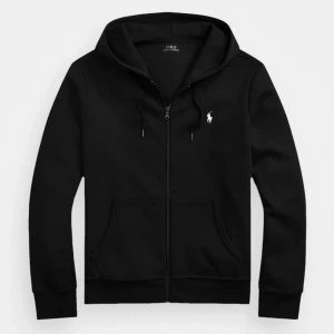Svart hoodie från Polo Ralph Lauren - Svart hoodie från Polo Ralph Lauren med dragkedja, huva med snörning och klassisk vit logga på bröstet. Tillverkad i 100% bomull och har två stora fickor framtill. Perfekt för en chill och stilren look. Priset kan diskuteras