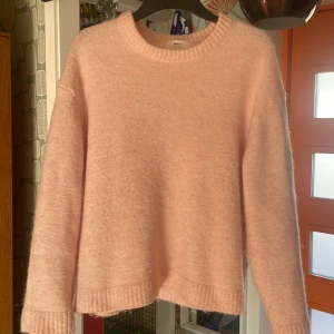 Ljusrosa stickad tröja Gina Tricot - Supermjuk och fluffig ljusrosa stickad tröja från Gina Tricot i ullblandning. Tröjan har rund hals, ribbade muddar och lång ärm. Perfekt för dig som gillar en enkel men söt look med cozy vibes.