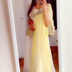 Festklänning, kaftan, långklänning L - Långklänning i ljusgul och vit med breda ärmar. Klänningen har en flowy passform och är tillverkad i ett tunt, lätt material som ger en elegant look. Klänningen är i storlek L men passar lika bra för S och M, jag som har storlek S passade den mig perfekt. 