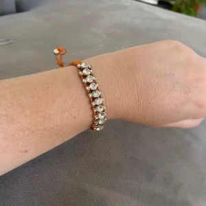 Armband från Baglady!  - Snyggt armband med orange flätad tråd och glittriga stenar. Armbandet är justerbart.  Perfekt för att ge en färgklick till din outfit!