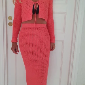 Virkat set kjol och cardigan - Säljer superfint aldrig använt kjolset med tight passform. Kjolen har en elastisk midja och är virkad i ett luftigt, hålmönstrat material som känns perfekt för varmare dagar. Tillhörande kort virkad kofta.