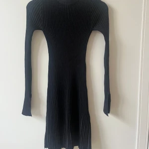 Ribbad klänning - Säljer en svart ribbad klänning i storlek XS. Klänningen har lång ärm, tight passform och är i ett stretchigt material. Aldrig använd!