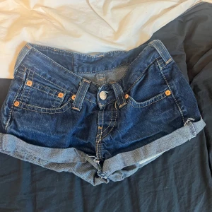 Levi's mörkblå jeansshorts - Snygga mörkblå jeansshorts från Levi's med klassiska fem fickor, uppvikta benslut och tydliga kontrastsömmar. Ikonisk läderpatch bak och Levi's-röd etikett på fickan. Perfekta för varma dagar och enkel att matcha med allt. Klippt själv.