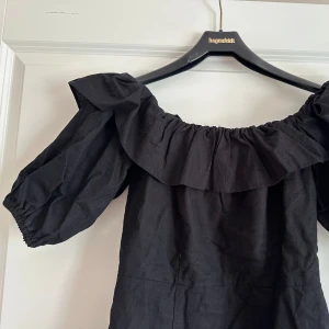 Svart offshoulder linnen klänning H&M - Supersnygg svart linnen kortklänning med offshoulder och puffiga korta ärmar. Perfekt för dig som gillar en stilren look. (Behöver strykas 😅)