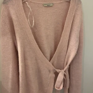 Ljusrosa kofta från Gina Tricot - Supermjuk ljusrosa kofta från Gina Tricot med knyt i sidan. Koftan är stickad och har långa ärmar. Tröjan är i storlek s, säljer då den inte använts på jätte länge eftersom jag växt ur den 