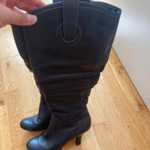 Svarta höga stövlar med klack - Snygga svarta stövlar i skinn med hög klack. Använt ett fåtal gånger. De passar både storlek 39 och 40.