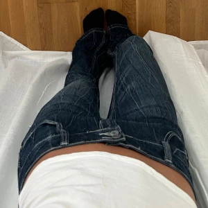 Mörkblå bootcut jeans med kontrastsömmar - Säljer ett par mörkblå bootcut jeans från Be Styled med tydliga kontrastsömmar och låg midja. Jeansen har dubbla knappar och snygga bakfickor. Midjemått rakt över 39cm, innerbenslängd 80cm