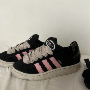 Adidas Campus sneakers svart/rosa - Svarta Adidas Campus sneakers med rosa ränder och breda ljusrosa skosnören. De rosa skosnörena har jag köpt själv. Det tillkommer de originala svarta snörena. Skriv vid funderingar!💓 