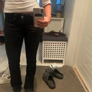 Svarta bootcut jeans med fickdetaljer - Säljer ett par svarta lowwaist jeans med bootcut passform och snygga fickor med silverknappar baktill.💗 