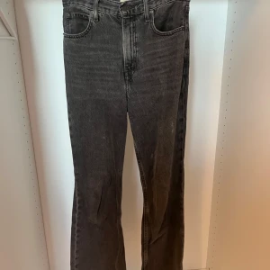 Levi's 517 svarta bootcut jeans - Säljer ett par svarta Levi's 517 jeans med bootcut passform. Jeansen har klassisk femficksdesign, hög midja och är tillverkade i slitstark denim. Snyggt tvättade med en lite urtvättad look och ikonisk läderpatch bak i midjan.