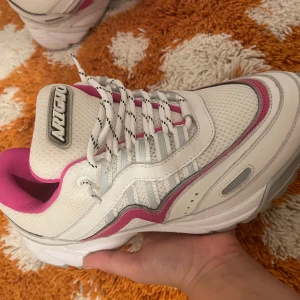 Chunky Axel Arigato vita och rosa sneakers - Chunky sneakers från Axel Arigato i vitt och rosa med coola detaljer i silver och grått. Ovandel i mesh och skinn, vita snören med svarta detaljer och rosa foder. Snygg logga framtill och sportig vibe. Perfekta för dig som gillar statement-sneakers.