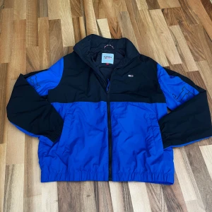 Blå och svart vindjacka Tommy Jeans - Vindjacka från Tommy Hilfiger i storlek s, finns tecken på användning, kom gärna med bud
