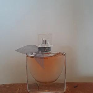 Lancôme La Vie Est Belle EdP 50ml - La Vie Est Belle från Lancôme är en ikonisk parfym i elegant glasflaska med en liten söt grå rosett vid halsen. Flaskan rymmer 50 ml och är påfyllningsbar. Doften är feminin, djup, mysig, en elegant blomdoft, med smakrika toner av vanilj, päron, jasmin och apelsinblomma - perfekt till hösten och vintern, men passar året runt. Den har en hyfsat stark doft som håller flera dagar. Endast öppnad och testad, annars som ny. Skriv om du har fler funderingar 🫶💗